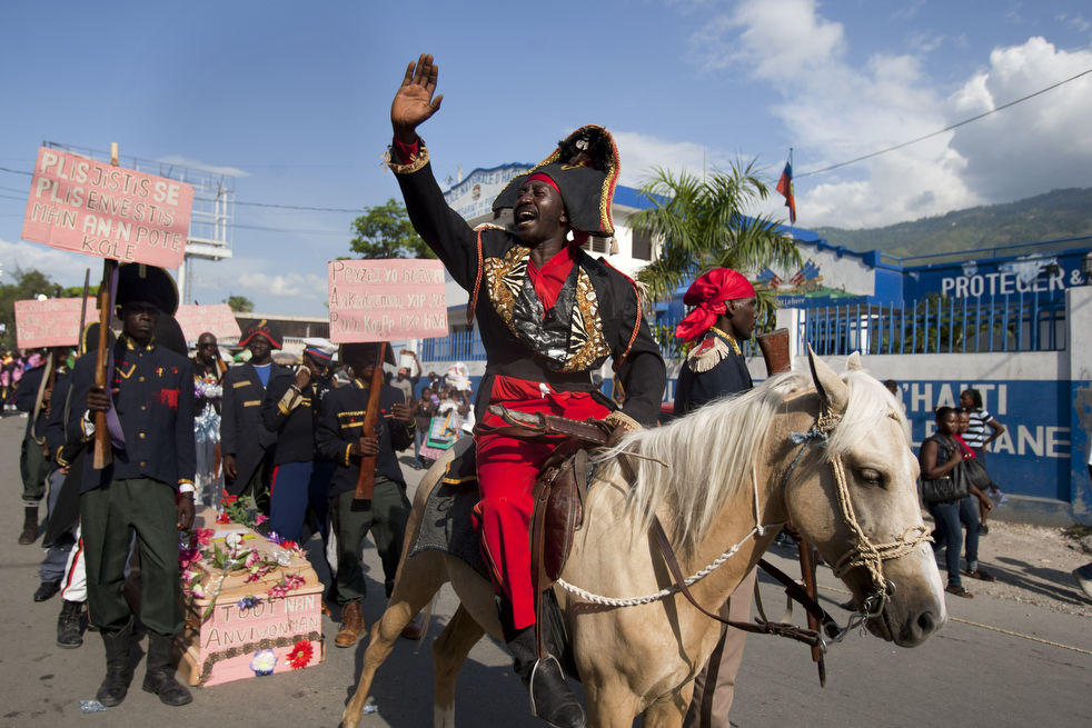 A man dressed as Haitian national hero Jean-Jacques Dessalines performs while his troops stand behind him with a coffin that serves as a symbol of the country's problems.