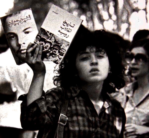 Iranian woman holding up the books Young Lenin and The History of the Russian Revolution
