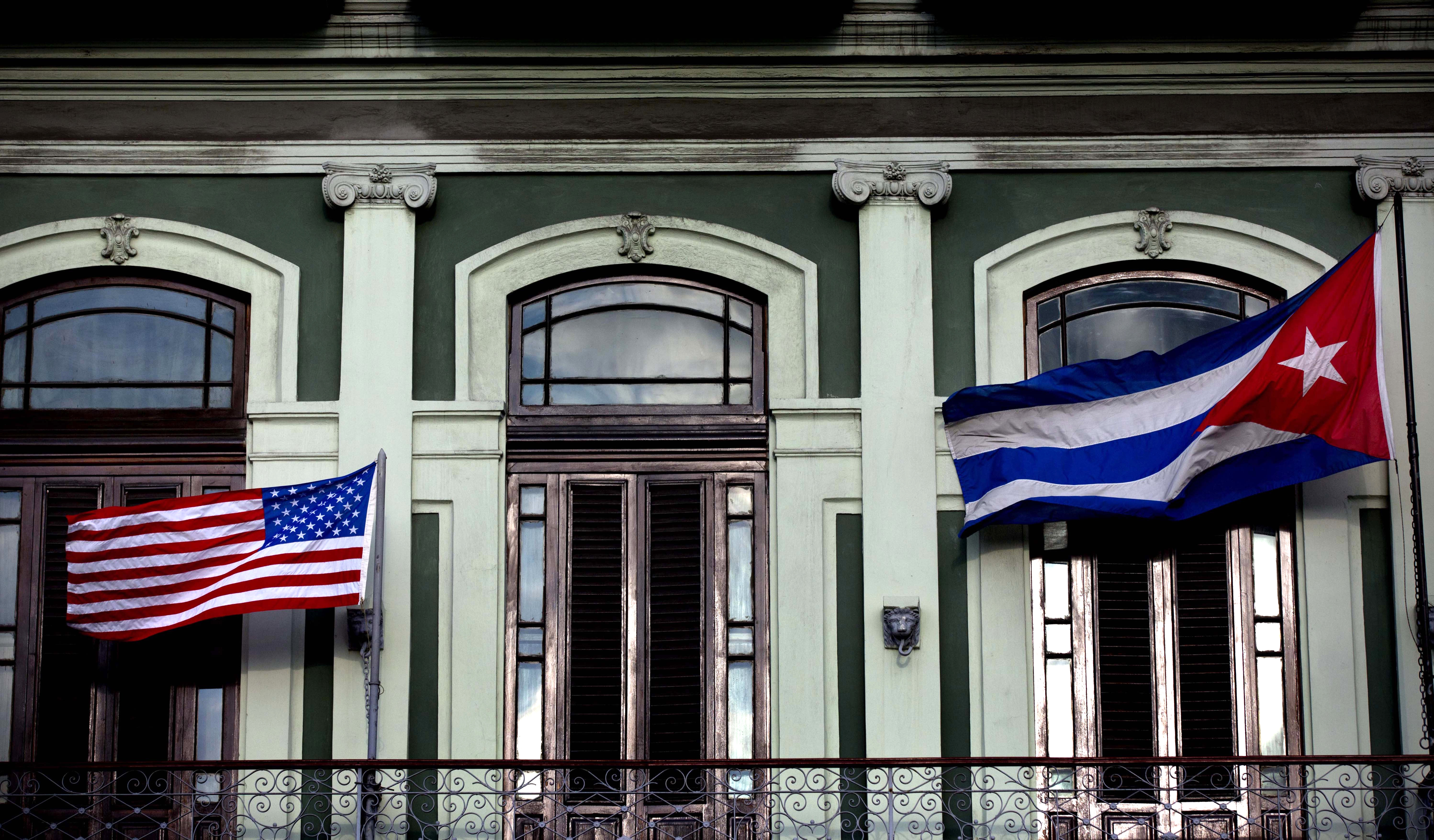 A Cuban and an American flag flying on a hotel balcony.