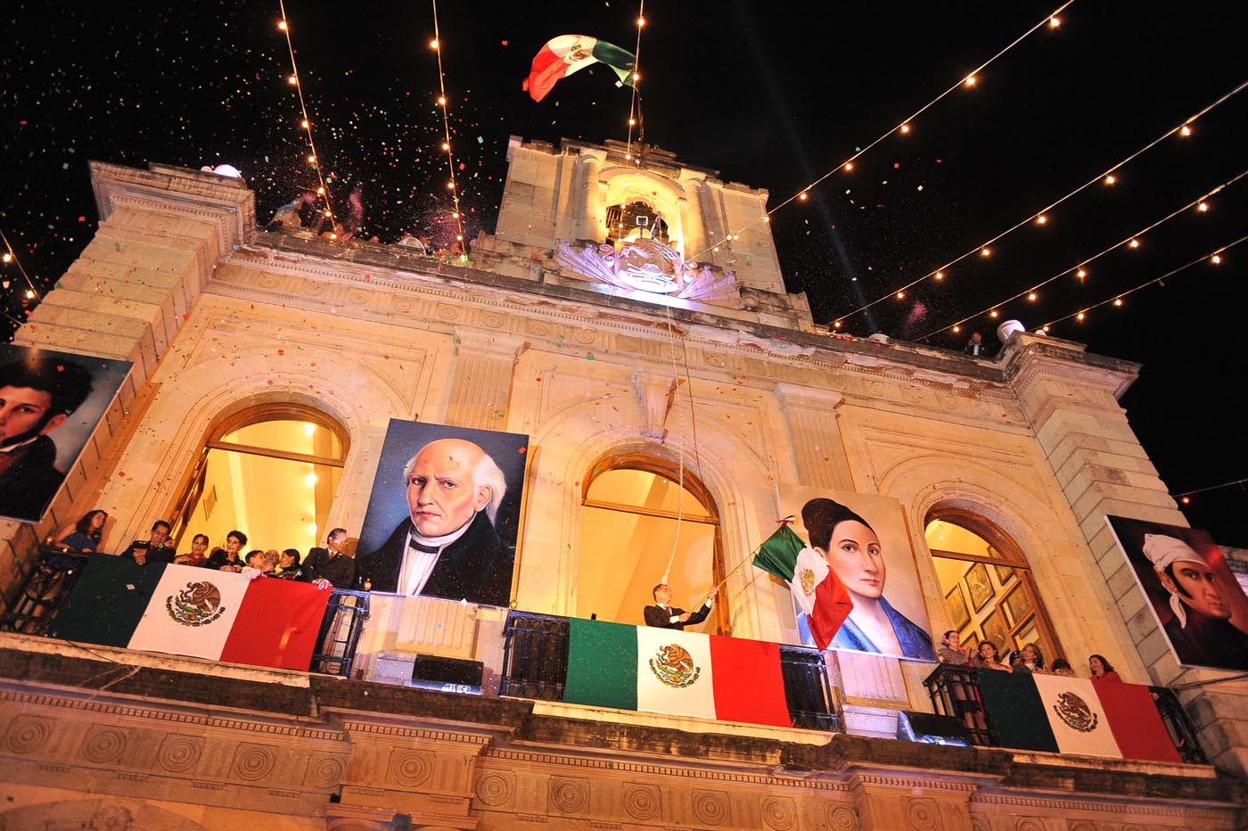 Facade of a building with Mexican flags and four portraits.