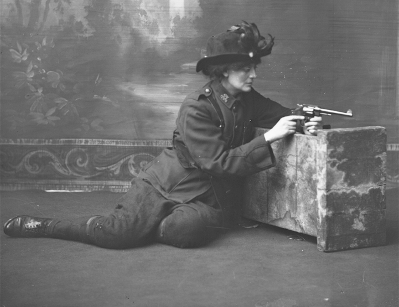 A woman sitting on the floor, holding a gun.