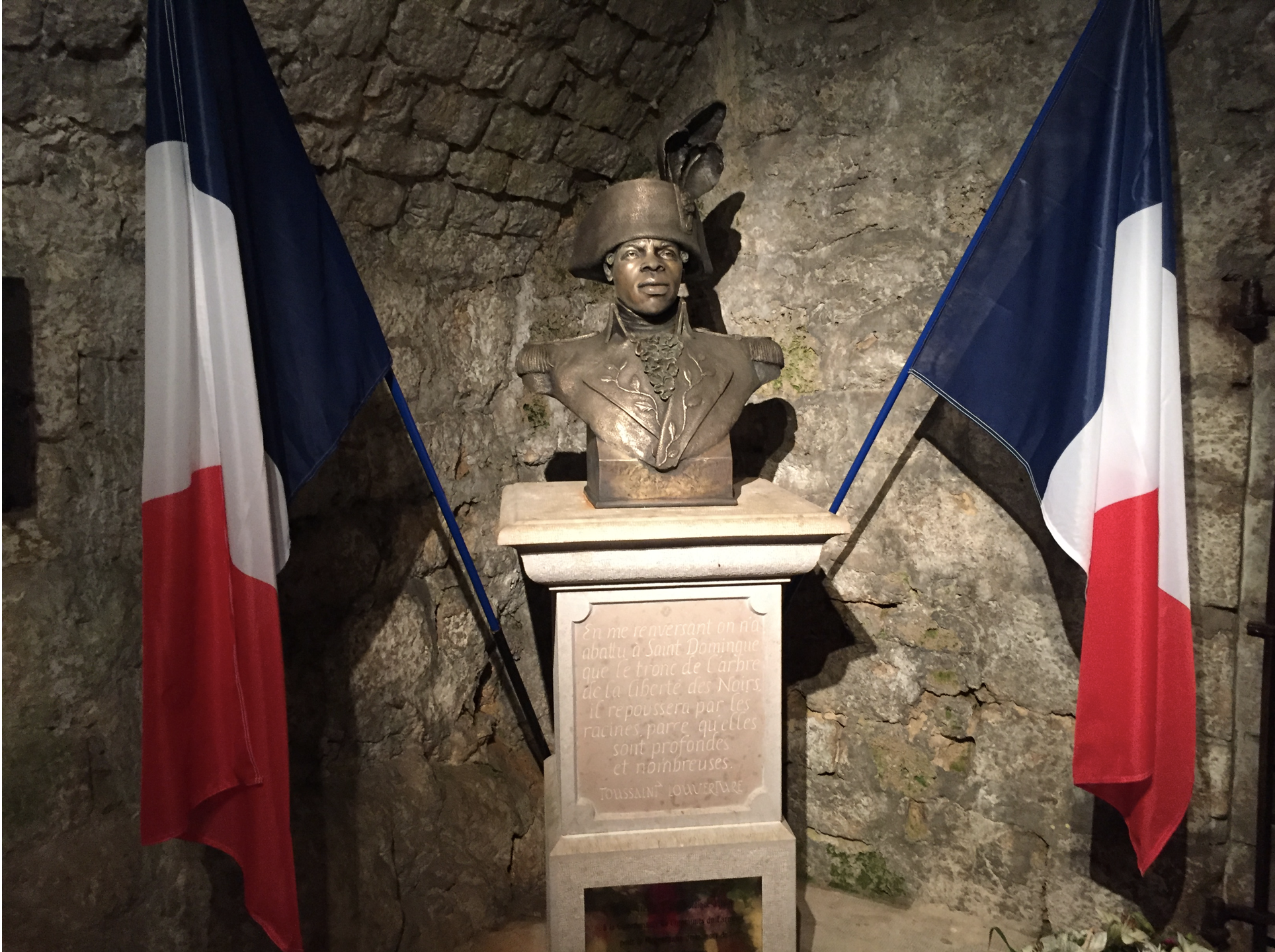 Bust of Toussaint L'ouverture surrounded by two French flags.