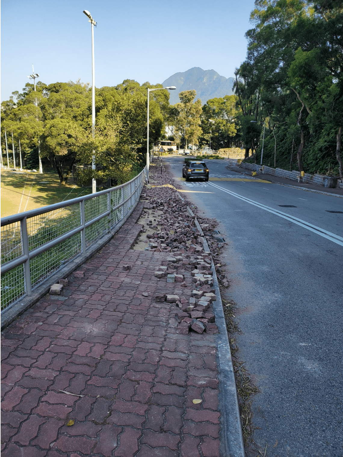 Sidewalk from which bricks have been removed and left on the side of the road.