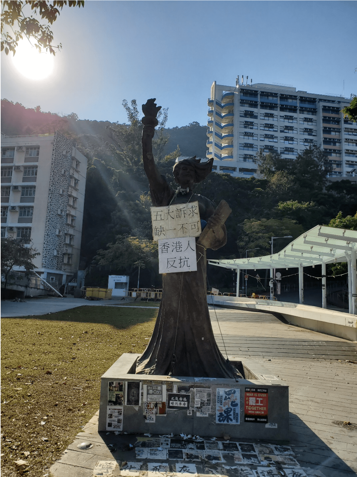 Statue wearing a cardboard sign around her neck with Chinese characters.