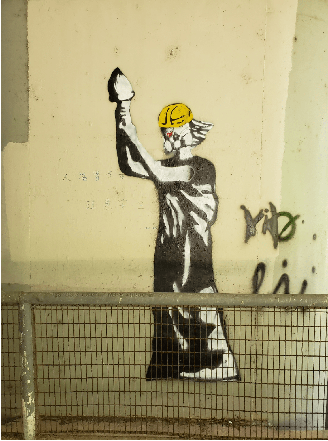 Graffiti of statue wearing a worker helmet.