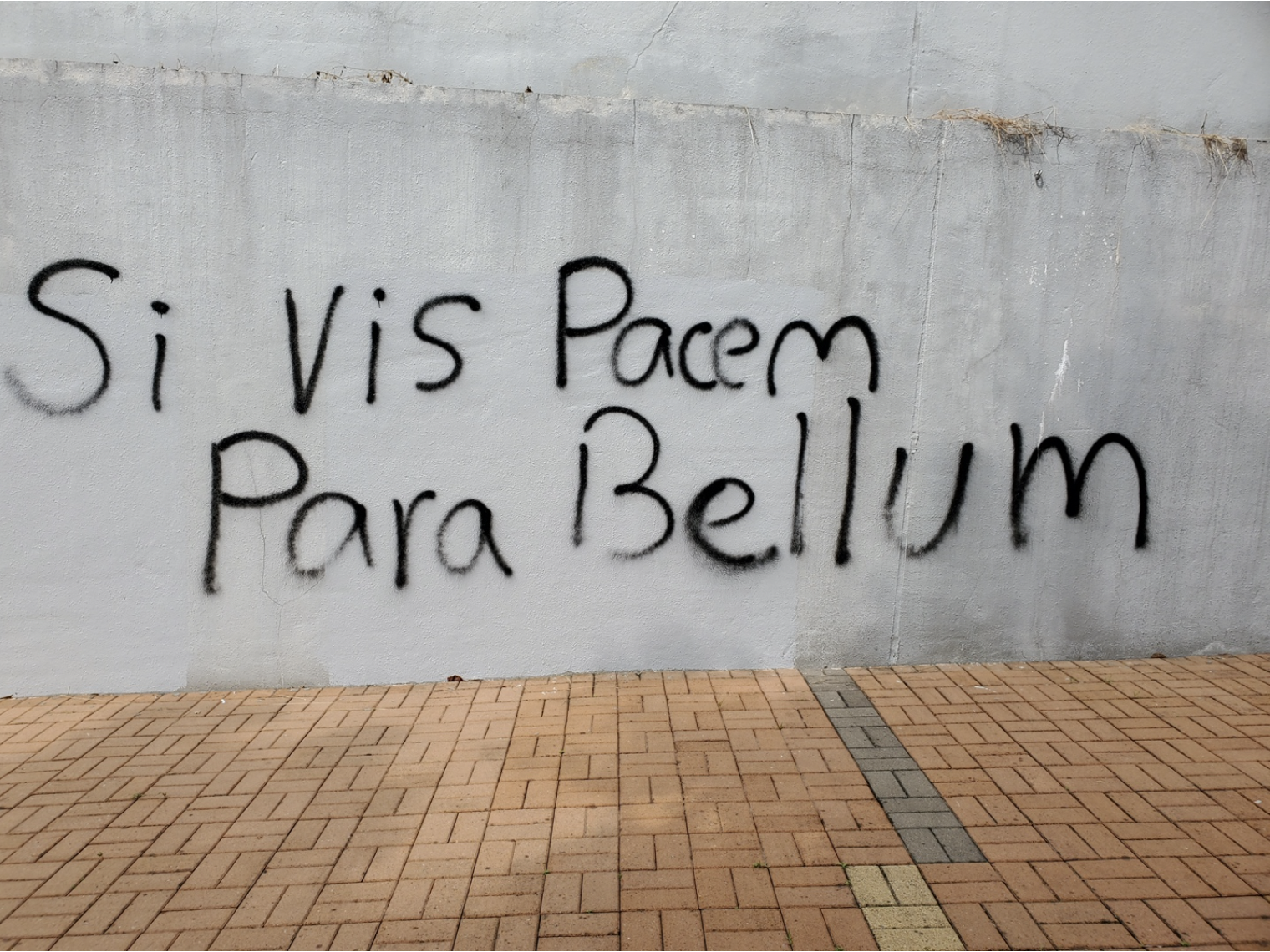 Graffiti on a wall that reads "If you want peace, prepare for war" in Latin.