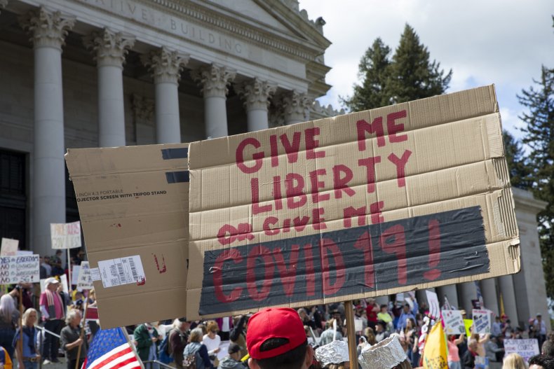 Protester holding a sign that reads "Give me Liberty or Give me COVID 19!"