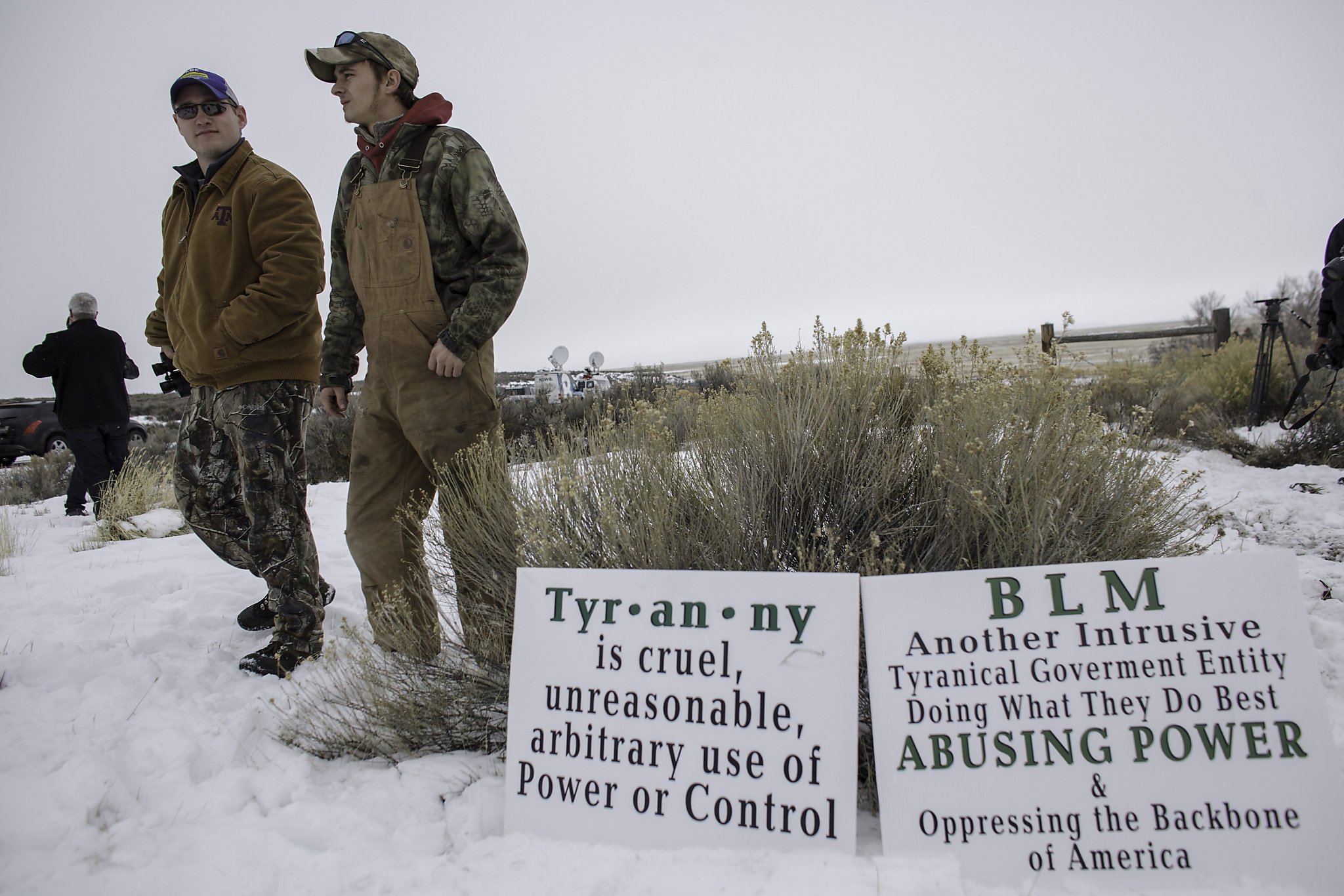 Two man standing next two signs that read oppose the abuse of power or control and the BLM movement.