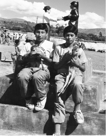 Two boys sitting and holding small animals.